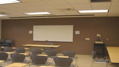 The whiteboard, seated desks, tables and projection equipment of LLC 132.